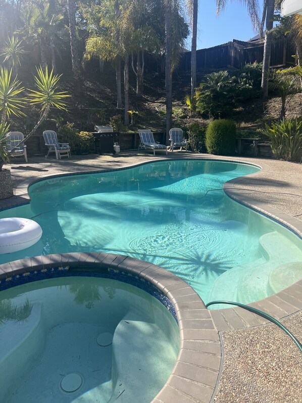Une piscine dont le bord est revêtu de carrelage, entourée de palmiers et de chaises longues.