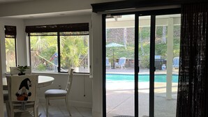 A spacious room with a large sliding glass door leading to a pool area. There is a dining table with chairs and a decorative chair with a pumpkin design. - Cheerful house 3 bed 4 bath pool house (Antioch)
