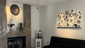 A modern living room with a fireplace, black sofa, and a ceiling fan. - Cheerful house 3 bed 4 bath pool house (Antioch)