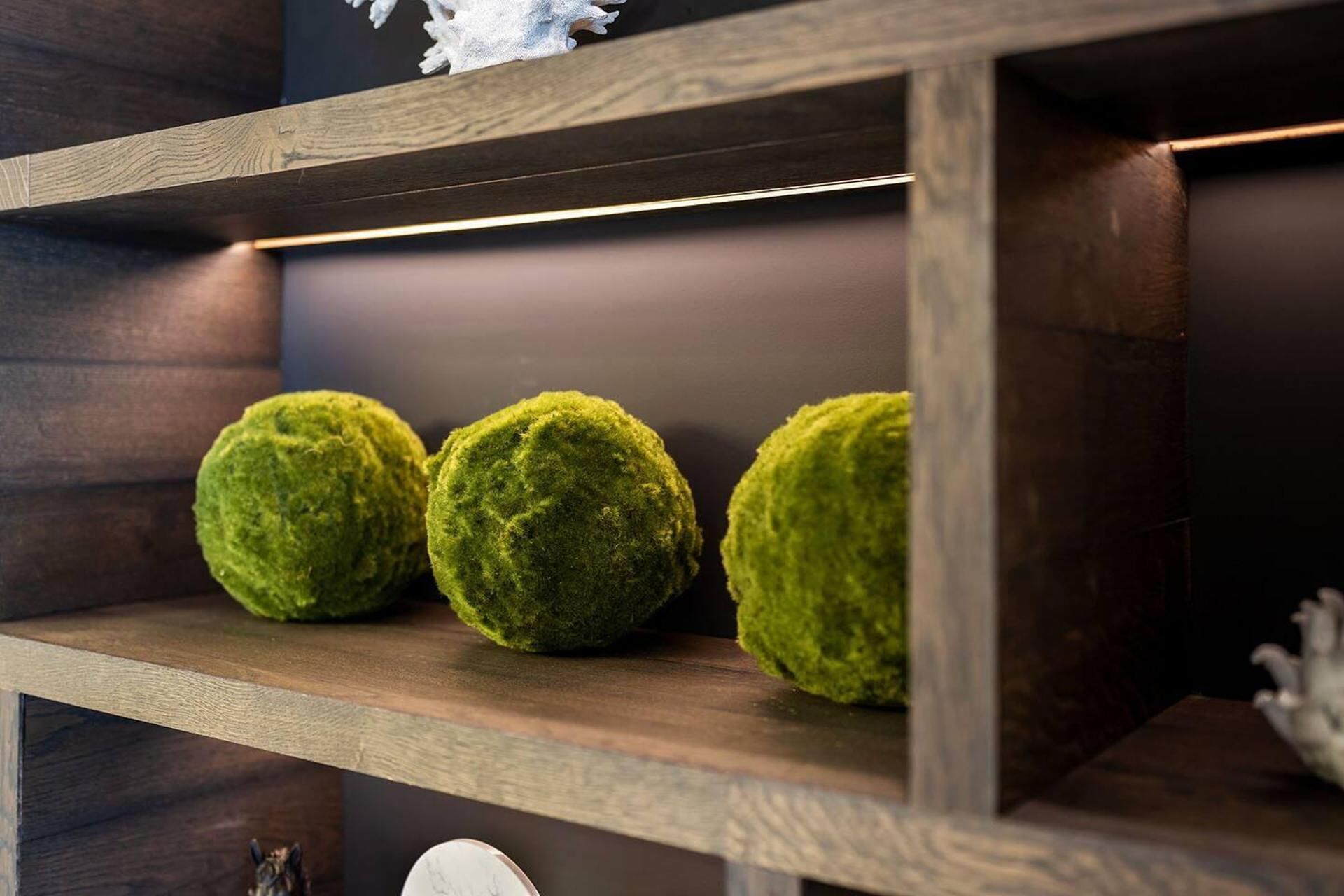 Un estante de madera con tres objetos esféricos verdes.
