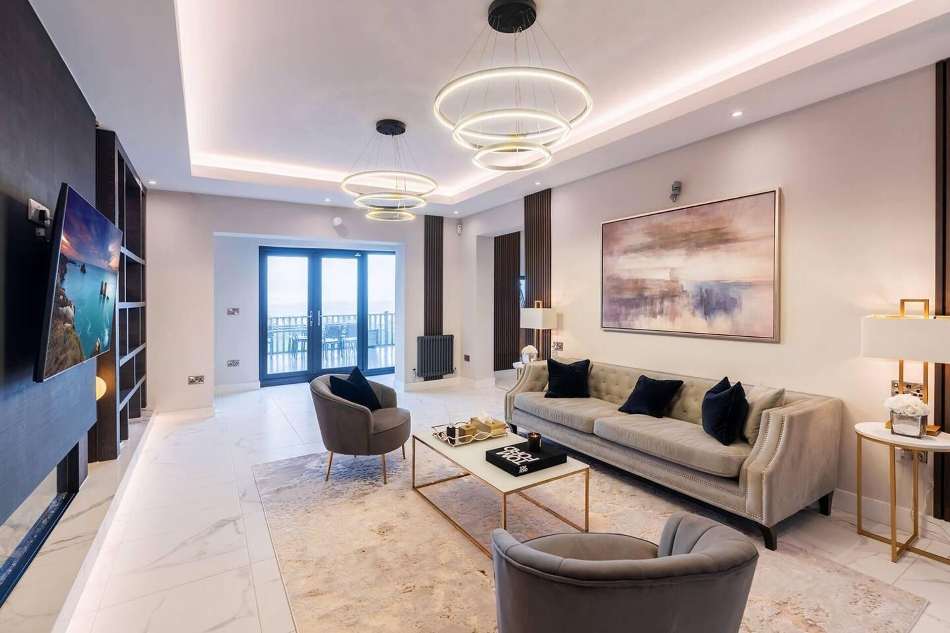 A modern living room with a sofa, armchairs, a coffee table, and a large painting on the wall.