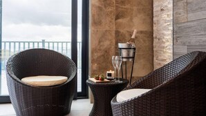 Un balcon avec des fauteuils en osier, une bougie et une bouteille de champagne.