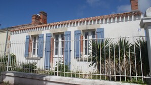 Un bâtiment à la façade blanche, aux volets bleus et au toit recouvert de tuiles.