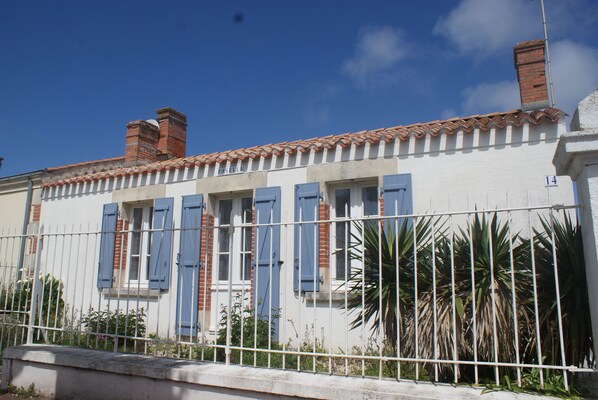 A building with a white facade, blue shutters, and a tiled roof. - Villa, large garden, wifi, 400m from the beach and 600m from the market (Saint-Gilles-Croix-de-Vie)