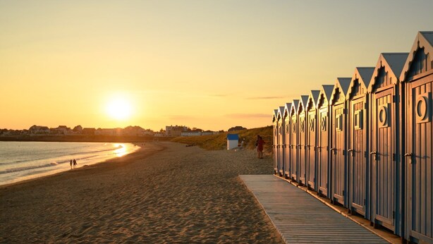 Une plage avec des cabanes en bois et une promenade en bord de mer.