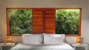 A bedroom with a large window, wooden shutters, a bed with white linens, and bedside lamps. - QUEBRADAHONDA ESTATE (La Vega)