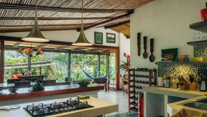 A modern kitchen with a gas stove, a dining area with a large window, and a hammock. - QUEBRADAHONDA ESTATE (La Vega)