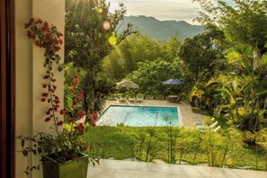 A pool area with a view of lush greenery and mountains in the background.