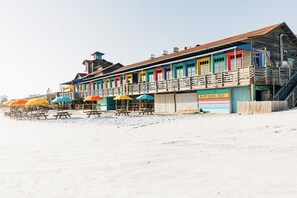 A beachside building with multiple colorful windows and a sign for a beach bar.