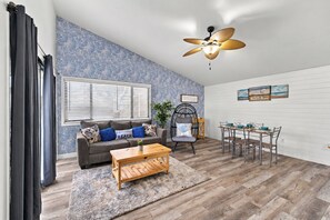 A living room with a sofa, coffee table, and dining area with chairs and a table.