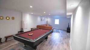 A spacious room with a pool table, a sofa, and a television. - •Vibrant 4 bedroom house 2 king beds in Ankeny• (Ankeny)