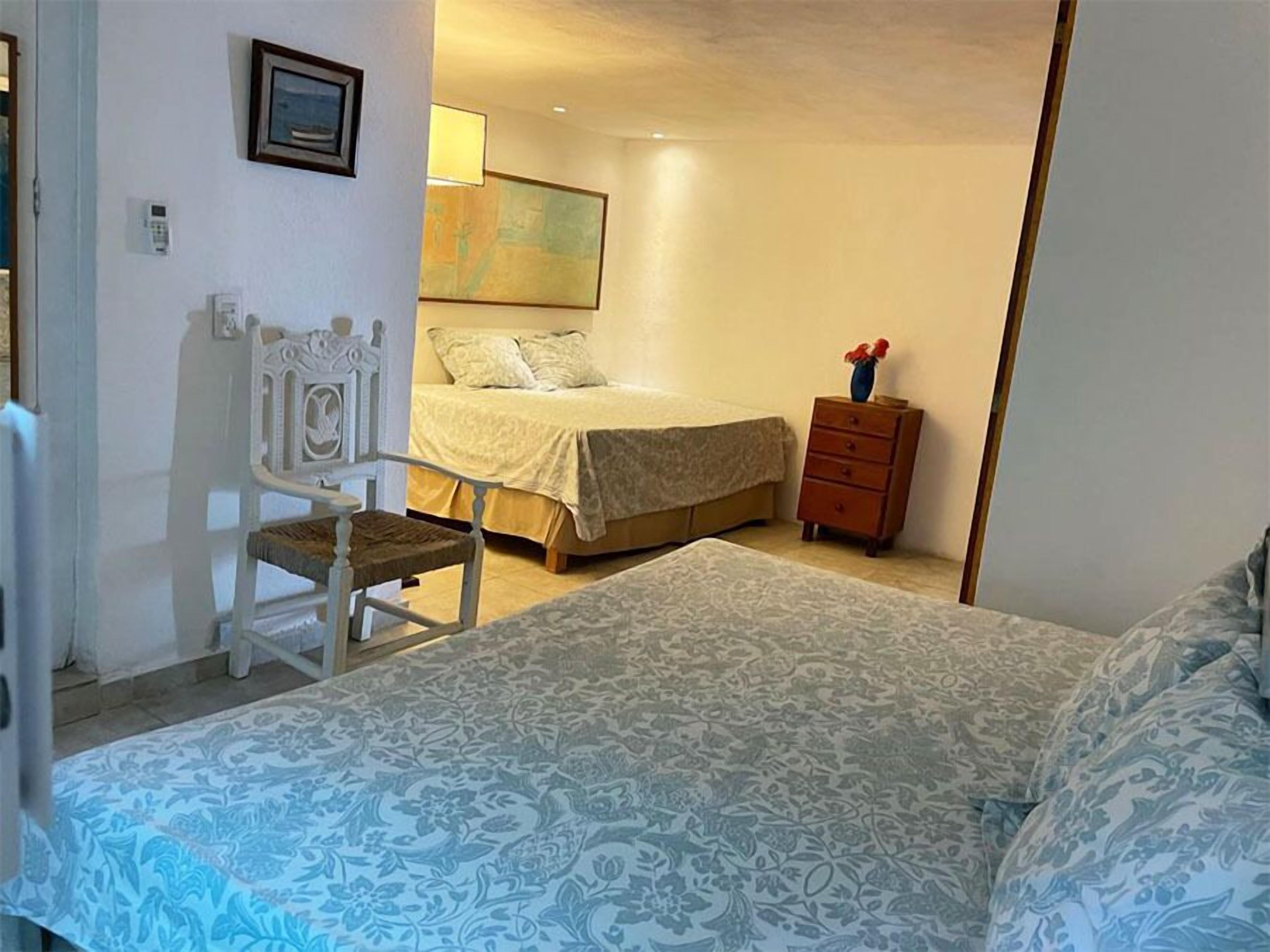 A bedroom with a bed, a chair, a nightstand, and a painting on the wall.