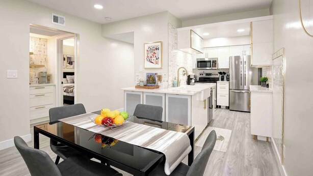 A modern kitchen with white cabinets, stainless steel appliances, and a central island with a fruit bowl. - Newly updated Modern 2 BR  Scottsdale Condo. (Scottsdale)
