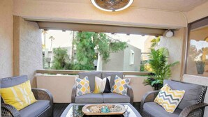A balcony with wicker furniture, a glass coffee table, and decorative pillows. - Newly updated Modern 2 BR  Scottsdale Condo. (Scottsdale)