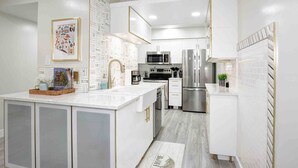 A modern kitchen with white cabinetry, stainless steel appliances, and a central island. - Newly updated Modern 2 BR  Scottsdale Condo. (Scottsdale)