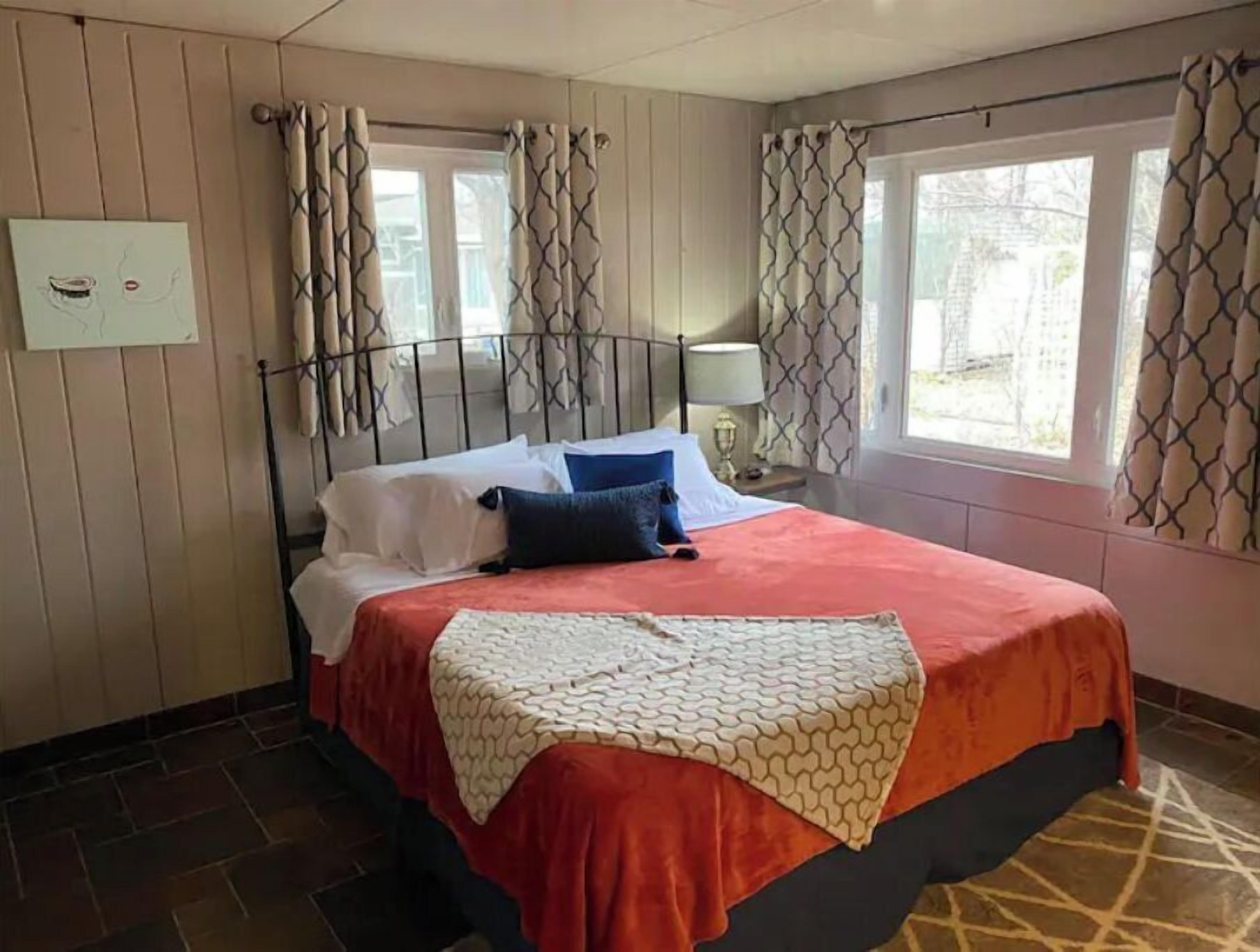 A hotel room with a bed, curtains, a nightstand, and a window.