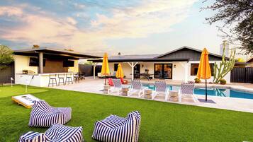 Une maison moderne dotée d’une piscine, d’un espace salon extérieur et d’un patio.