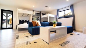 A modern hotel room with bunk beds, a sofa, a coffee table, and a large window. - The Oasis: Luxe Heated Pool | Big Backyard | Outdoor Bar & BBQ for Large Groups (Scottsdale)