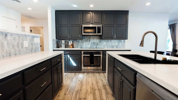 A modern kitchen with dark cabinetry, a stainless steel microwave, an oven, and a sink. - The Oasis: Luxe Heated Pool | Big Backyard | Outdoor Bar & BBQ for Large Groups (Scottsdale)
