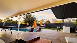 An outdoor patio with a pool, seating areas, and umbrellas. - The Oasis: Luxe Heated Pool | Big Backyard | Outdoor Bar & BBQ for Large Groups (Scottsdale)