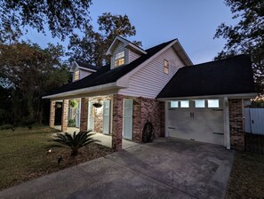 Une maison à deux étages avec une façade en briques, un garage et une véranda couverte.