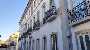 Une rangée de bâtiments blancs, dotés de fenêtres en arc de cercle et de balcons en fer forgé noir.