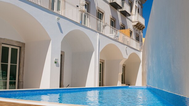 Une piscine dotée d’une terrasse en bois, d’arcs blancs et d’un balcon agrémenté de balustrades.