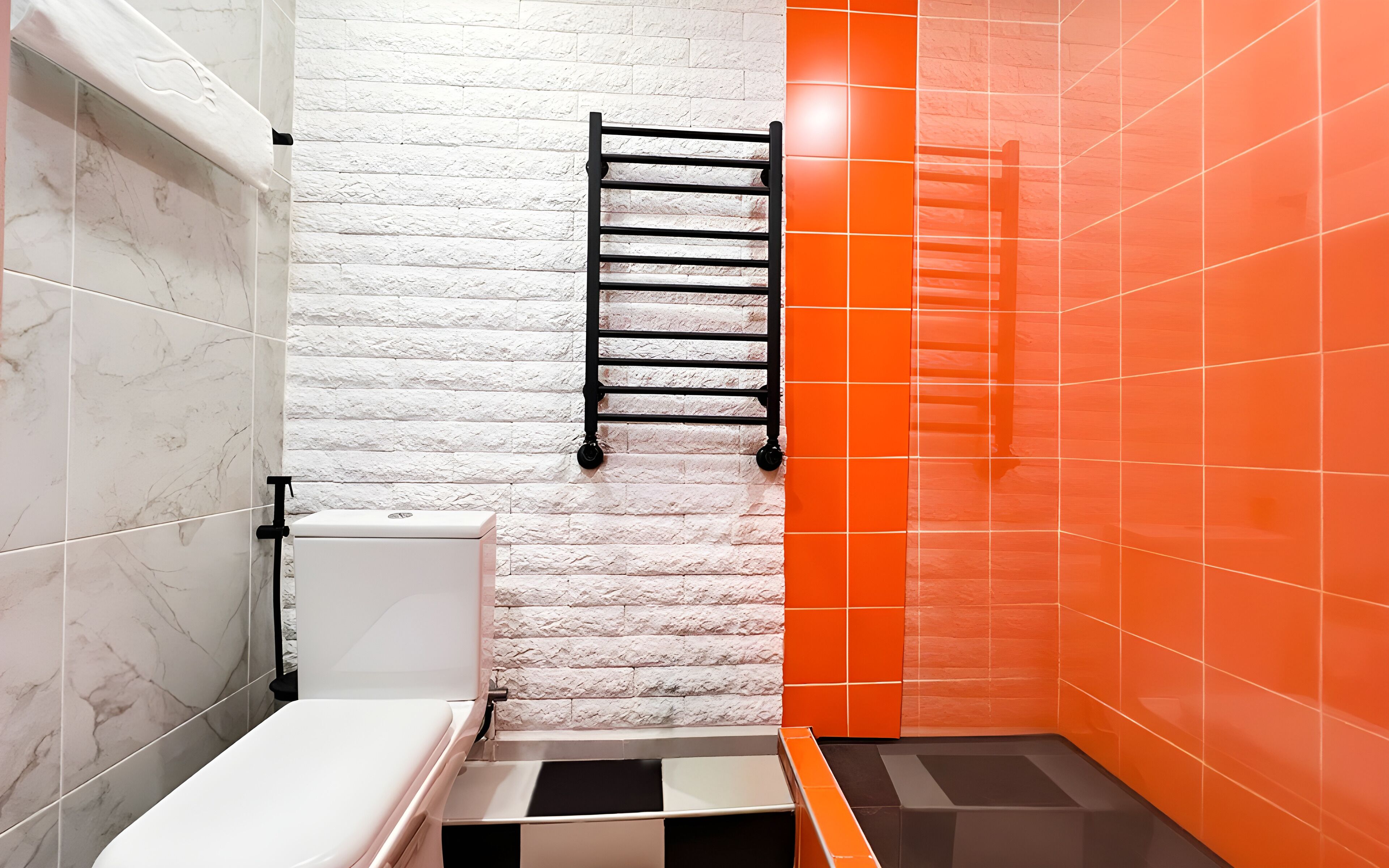 Une salle de bain avec un mur en marbre blanc, un porte-serviettes noir et des carreaux orange.