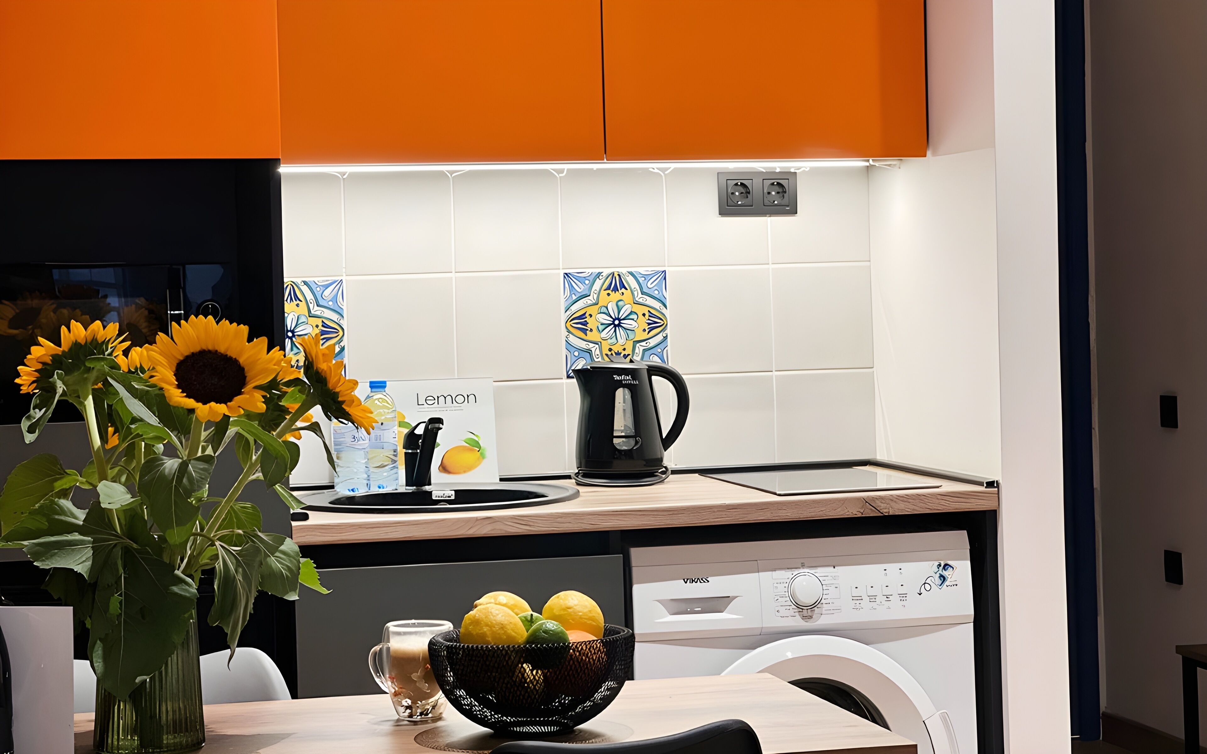 A modern kitchen with a dishwasher, a coffee maker, and a bowl of lemons.