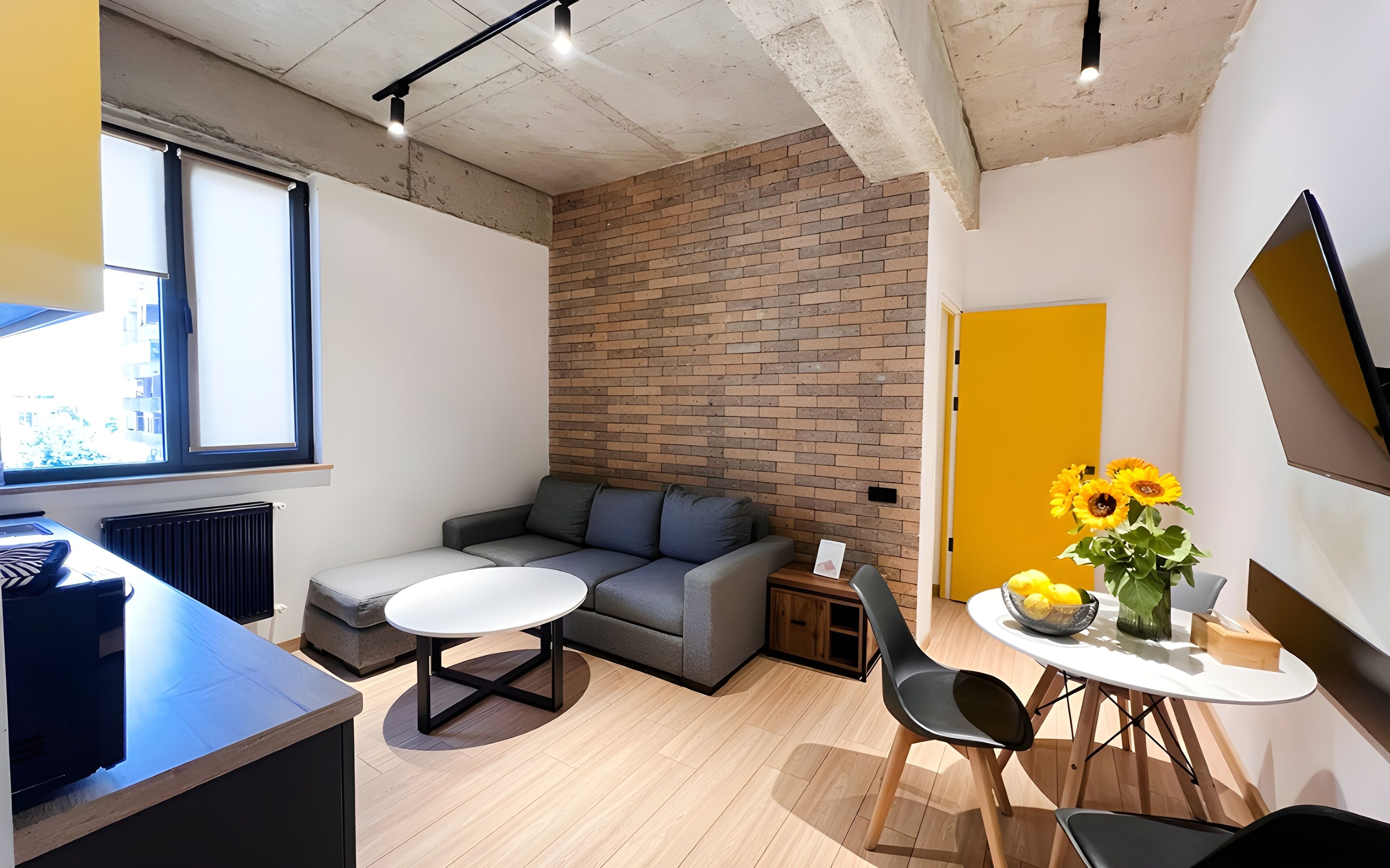 Un espace de vie moderne avec un canapé gris, une table ronde et une porte jaune.