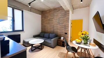 Un espace de vie moderne avec un canapé gris, une table ronde et une porte jaune.