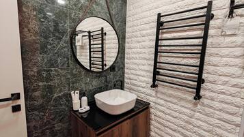 A bathroom with a round mirror, a towel rack, a sink, and a wooden cabinet.