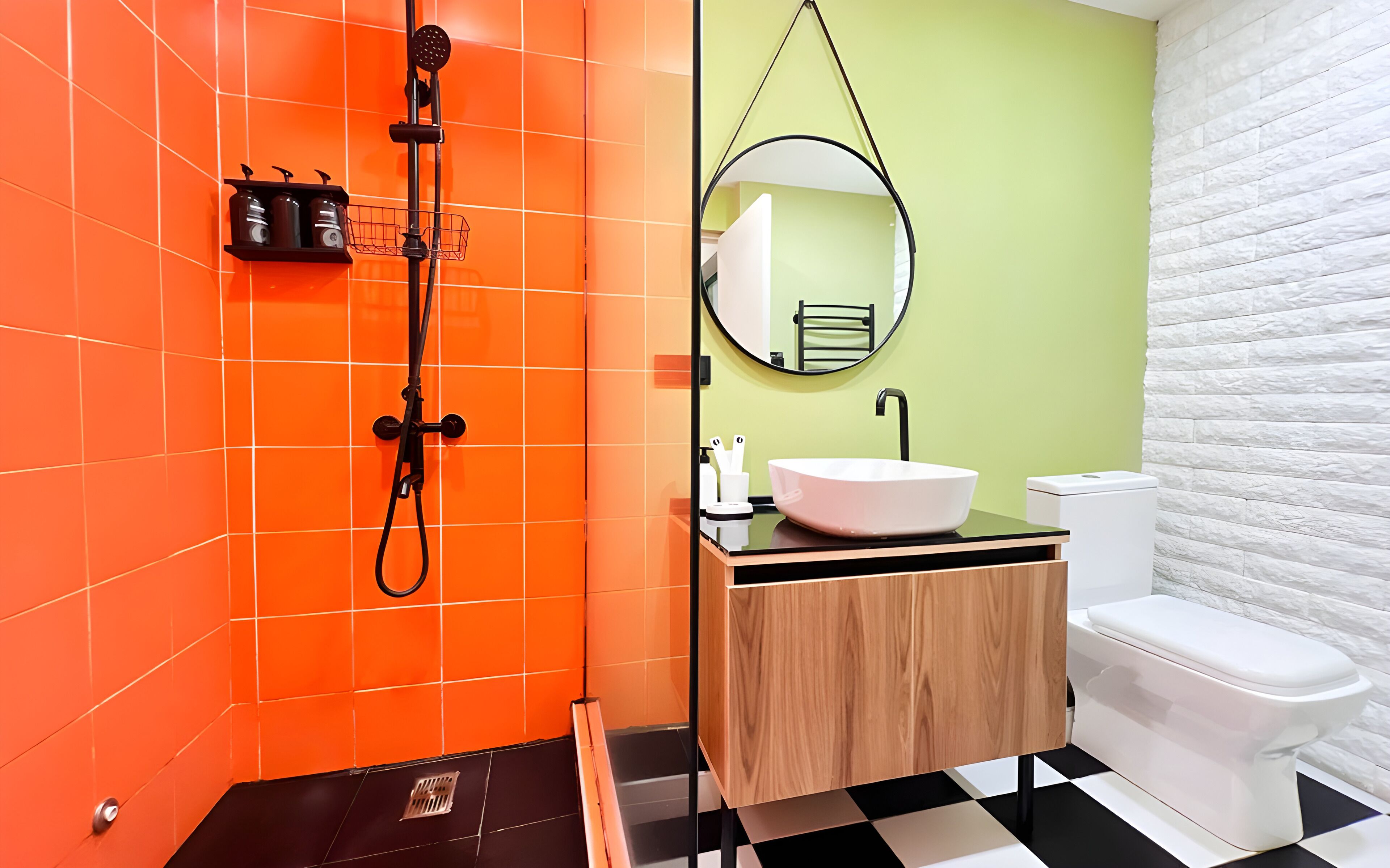 A bathroom with orange tiled walls, a wooden vanity, a white sink, and a toilet.