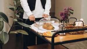 Une table avec un panier à pain, un cloche de verre recouvrant une assiette et un vase rempli de fleurs.