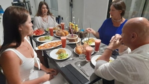Un groupe de personnes est réuni autour d’une table, où se trouvent divers plats et boissons.