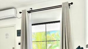 Une chambre d’hôtel avec un lit, une fenêtre avec des rideaux et un climatiseur fixé au mur.