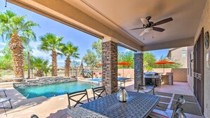 An outdoor pool area with a covered patio, seating, and a view of the pool.