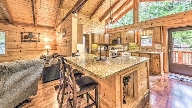 A log cabin interior with a kitchen, dining area, and a cozy seating area with a couch and chairs. - Updated Ruidoso Cabin w/ Spacious Deck & View (Ruidoso)