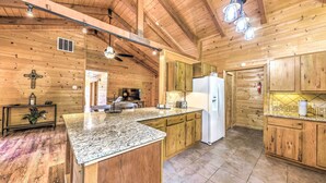 A kitchen with wooden cabinets, granite countertops, a ceiling fan, and a refrigerator. - Updated Ruidoso Cabin w/ Spacious Deck & View (Ruidoso)