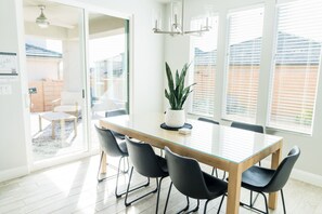 Un coin repas avec une table à plateau en verre, des chaises noires et une plante en pot.