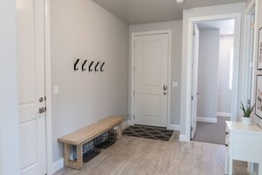 A hallway with a bench, a door, and a small table with a plant.