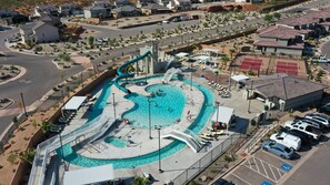 Vue aérienne d’un complexe hôtelier doté d’une grande piscine, d’un toboggan aquatique et de courts de tennis.