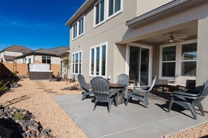 Une façade de maison avec un patio aménagé, comprenant des meubles d’extérieur et un espace salon abrité.