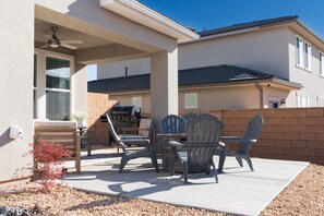 An outdoor patio with a grill, chairs, and a small table.