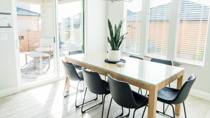 Un comedor con mesa de vidrio, sillas negras y una planta en maceta.