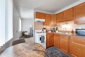 A modern kitchen with wooden cabinets, a white stove, and a granite countertop.
