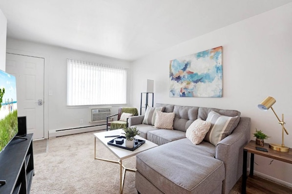 A living room with a grey sofa, a coffee table, a painting, and a lamp.
