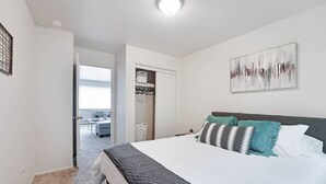 Ein Schlafzimmer mit einem großen Bett, einem Kleiderschrank mit Kleidung und einem Bild an der Wand.