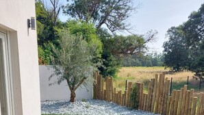 An outdoor patio area with a glass-top table and wicker chairs. - Charming Bas de villa beach walking natural site (Venzolasca)