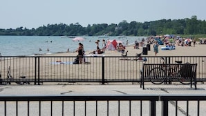 Een strand met een metalen hekwerk, een fiets en een bankje.